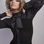Fashion model wearing Rosanna wig with tousled hair and black outfit.